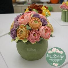 a vase filled with flowers on top of a white table next to cupcakes