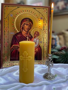 a lit candle sitting on top of a table next to a card and an icon