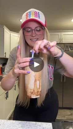 a woman in glasses and a hat holding up a cup with the word happy on it