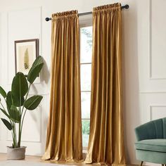 a living room with a couch, chair and window covered in gold drapes next to a potted plant