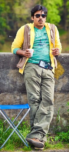 a man leaning against a stone wall with sunglasses on