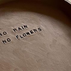 there is no rain, no flowers written on the side of a stone bowl in front of a brick wall