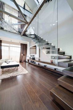 a living room filled with lots of furniture next to a stair case on top of a hard wood floor