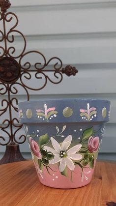 a blue and pink flower pot sitting on top of a wooden table next to a metal object