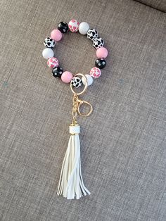 a close up of a bracelet with beads and tassels on a couch surface