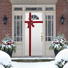 a white door with a red bow on it and two planters filled with snow