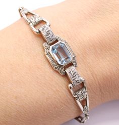 This iconic Art Deco dates from the 1920s. The bracelet is silver with a Synthetic Blue Spinel gemstone in the centre. The silver has a geometric design true of the period, with an intricate design on the silver. Marking: 835 AG. Size: 6 1/2 inches long (17 cm) Weight: 8 grams Condition: Fantastic condition. The clasp is working as it should. The stone is very bright with no damage. True flapper girl style bracelet. Find more unique Art Deco jewellery in my shop: https://www.etsy.com/uk/shop/per Art Deco Gemstone Bracelet For Formal Occasions, Vintage Silver Bracelets With Diamond Cut, Art Deco Hallmarked White Gold Bracelets, Art Deco Hallmarked White Gold Bracelet, Classic Sterling Silver Gemstone Bracelet For Formal Occasions, Art Deco Anniversary Bracelet, Sterling Silver Art Deco Jewelry For Formal Events, Antique Silver Gemstone Bracelet, Antique Gemstone Bracelets For Formal Occasions