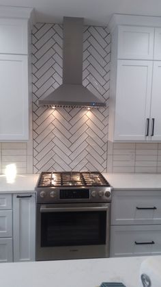 a stove top oven sitting inside of a kitchen next to white cupboards and drawers