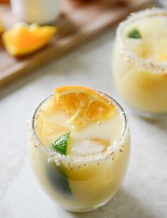 two glasses filled with orange juice and garnished with sugar on the rims