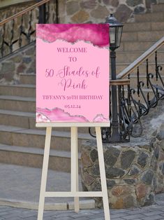 a welcome sign stands in front of some stairs and steps with pink paint on it