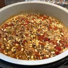 a large white bowl filled with soup on top of a stove