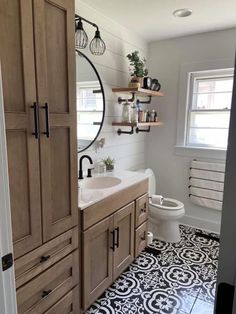 a white toilet sitting next to a bathroom sink under a mirror on top of a wooden cabinet