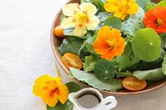 a bowl filled with lots of flowers next to a cup of coffee