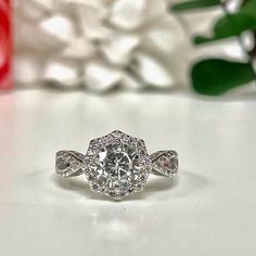 a diamond ring sitting on top of a table next to red roses and white flowers