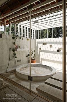 a bath tub sitting inside of a bathroom next to a tiled floor and wall covered in plants