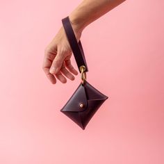 a hand is holding an empty wallet on a pink background with a gold ring around it