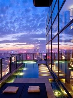 an outdoor swimming pool in front of a large window at night with the city lights lit up