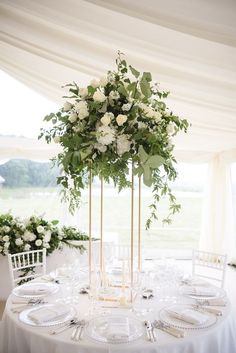 an image of a table setting with white flowers on the centerpiece and place settings