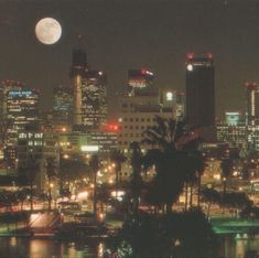 the city is lit up at night with full moon