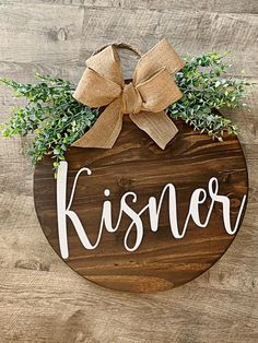 a wooden sign that says kissner with a bow hanging on the side of it