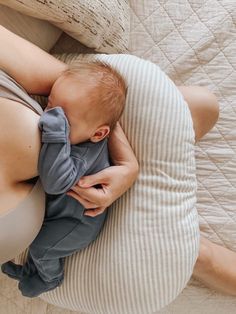 a woman laying on top of a bed holding a baby