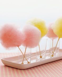 four cotton candy lollipops sitting on a tray with pink and yellow balls