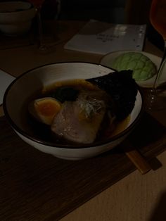 a bowl filled with meat and vegetables on top of a wooden table