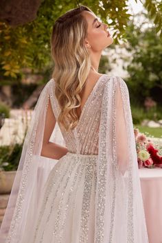 a woman in a wedding dress standing next to a table with flowers and greenery