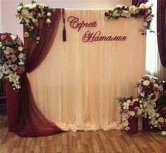 a stage set up with flowers and decorations for an event or wedding reception in the middle of a wood floored room