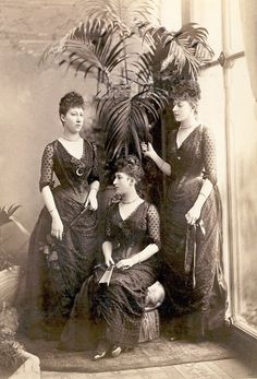 an old photo of three women sitting next to each other in front of a potted plant