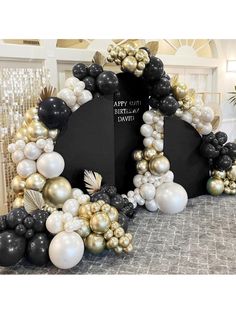 a black and gold birthday arch with balloons