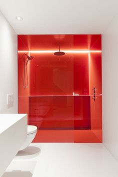 a bathroom with red glass walls and white flooring, along with a walk in shower