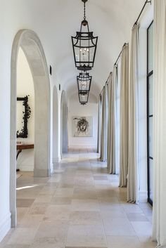 the hallway is lined with white walls and arched doorways, along with an iron hanging lantern