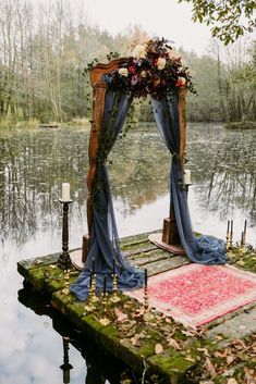 an outdoor ceremony setup with flowers and blue draping on the ground next to water