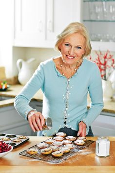 an older woman is making cupcakes in the kitchen with her hands on the table