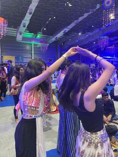 two women standing in front of a crowd with their hands on their hipss and looking at the ceiling