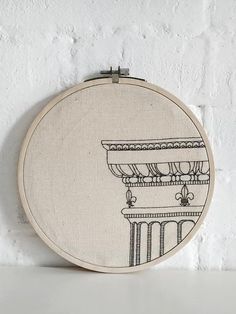 a white wall hanging with a black and white embroidery pattern on it's side