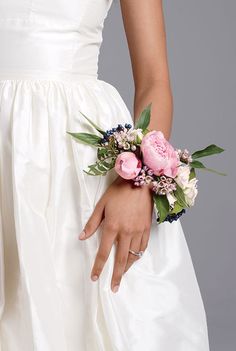 a woman wearing a wedding dress holding a bouquet of flowers in her hand with both hands