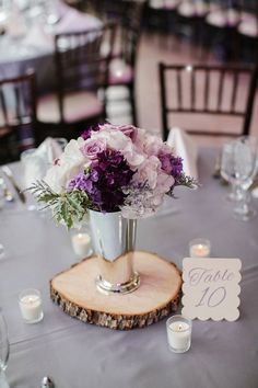 the centerpieces on this table are filled with purple and white flowers