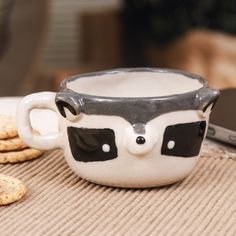 a white cup with black eyes sitting on top of a table next to crackers