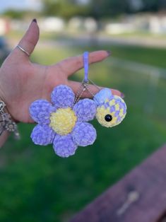 a person's hand holding a small stuffed animal with flowers attached to the thumb