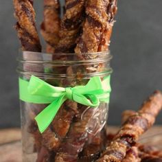 a jar filled with candies sitting on top of a wooden table next to a green bow