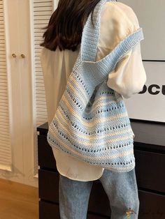 the back of a woman carrying a crocheted blue and white tote bag