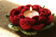 a crocheted candle holder with a lit candle in it