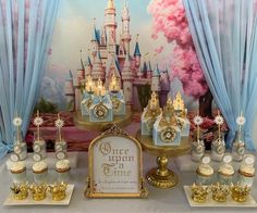 a table with cupcakes and cakes on it in front of a castle backdrop