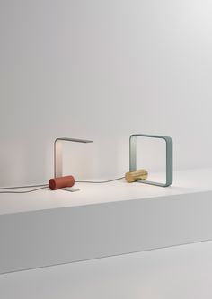 three different colored objects sitting on top of a white shelf next to eachother