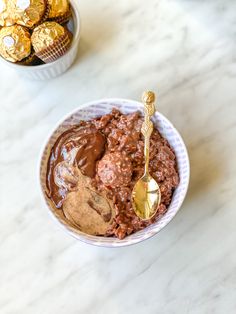 a white bowl filled with chocolate pudding next to a cup of gold foiled oreos