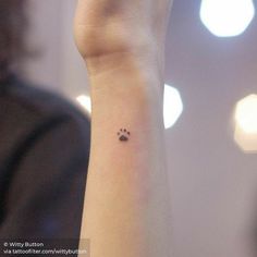 a woman's wrist with a small dog paw tattoo on the left side of her arm