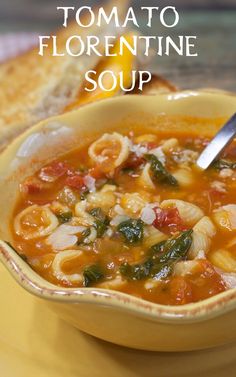 a yellow bowl filled with tortellini soup on top of a table next to a slice of bread