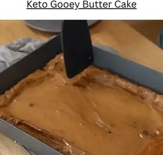 a cake in a pan with some frosting on it and someone using a knife to cut the cake